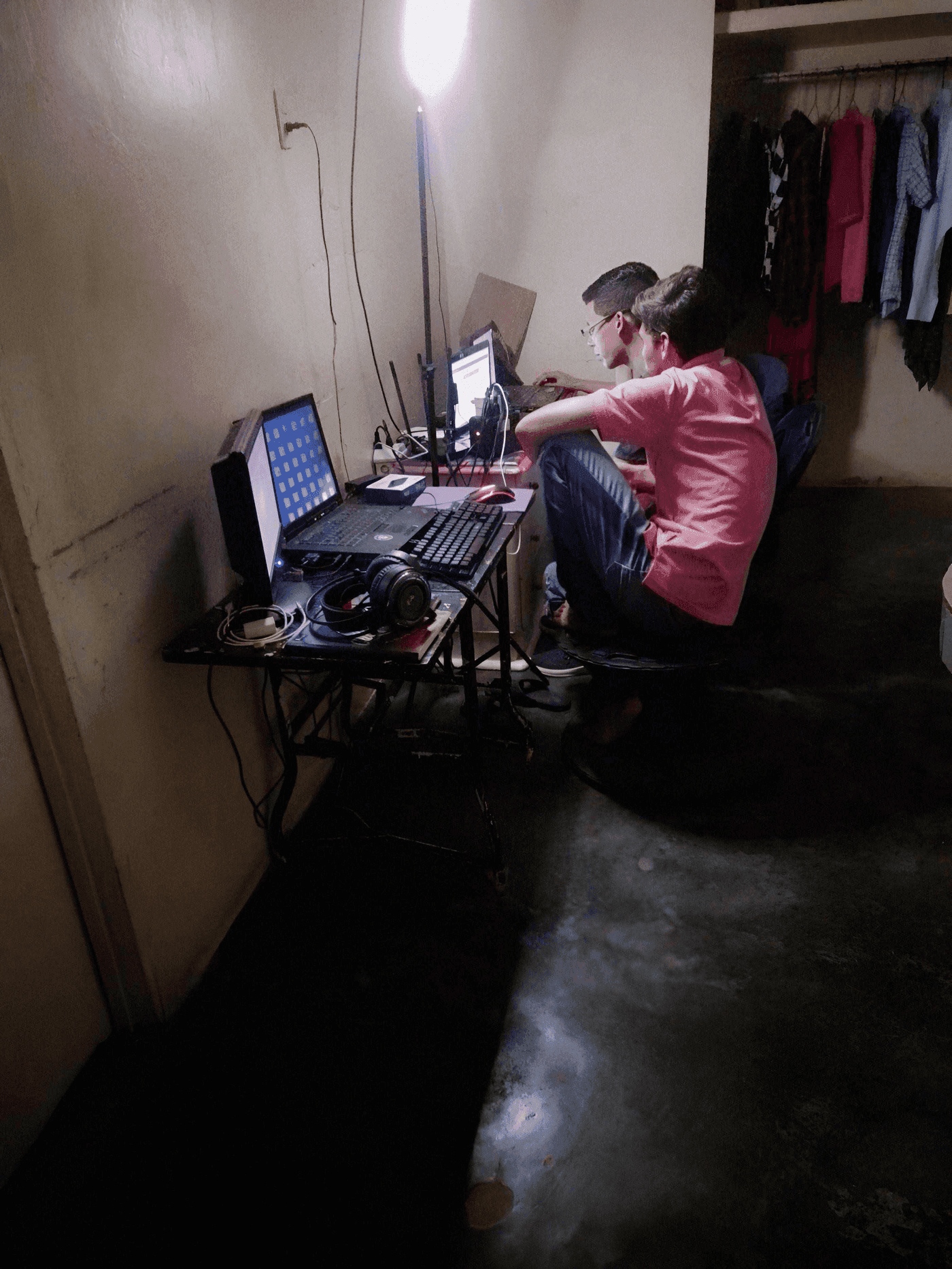 Orlando Briceño and his wife at a small desk with two computers in a modest room